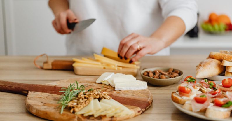 Charcuterie Boards - Person Slicing Cheese on Brown Wooden Chopping Board