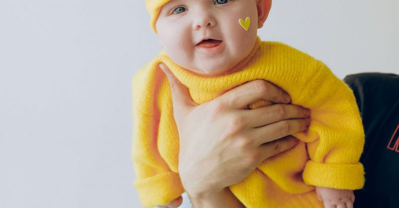 Tenderizing - Crop parent holding smiling baby in arms against gray wall in room