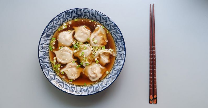 Dumplings - Round White and Blue Ceramic Bowl With Cooked Ball Soup and Brown Wooden Chopsticks