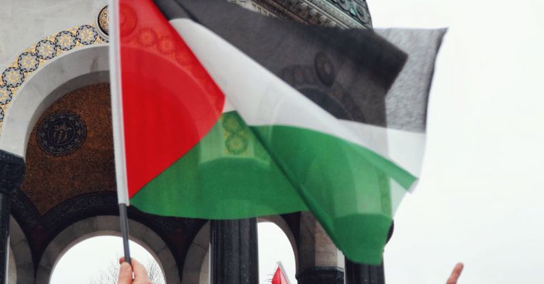 Gluten-Free - Palestine flag in front of a building with people holding it