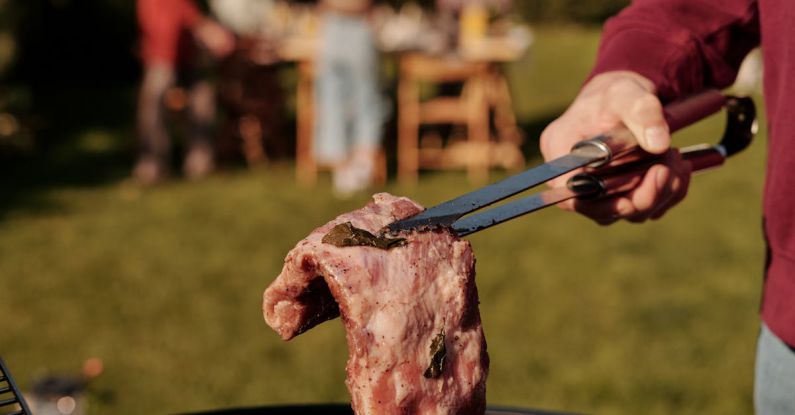 Backyard BBQ - Close-Up Shot of a Person Grilling Steak